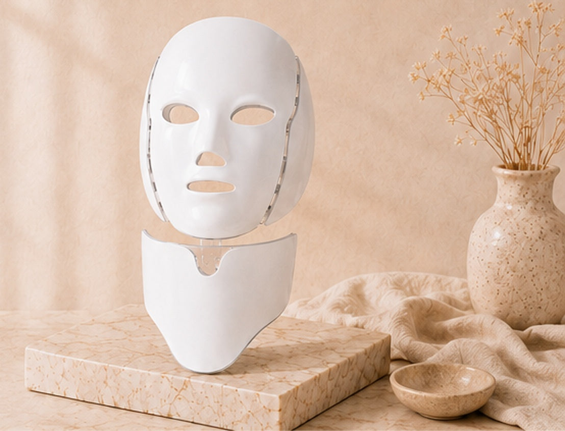 Lumora face and neck LED mask on a warm stone pedestal